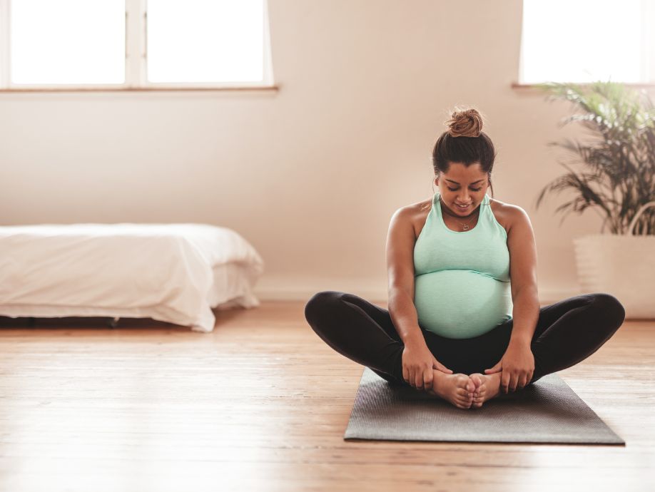 a pregnant woman practicing butterfly pose in a prenatal yoga class