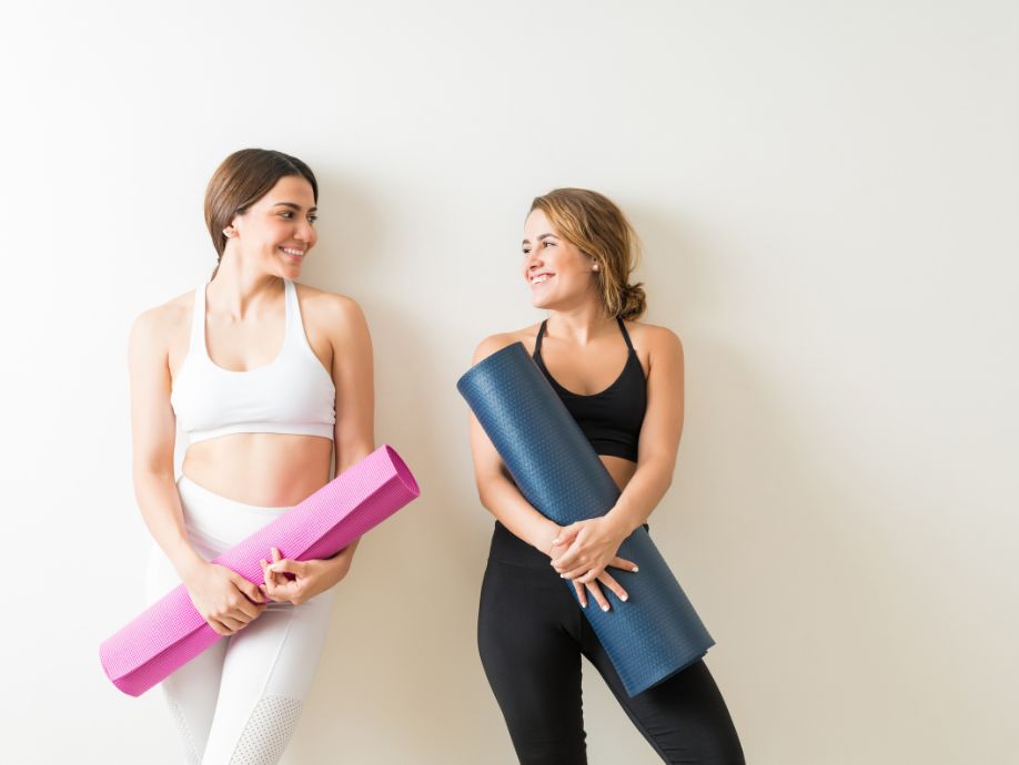 two women holding yoga mats